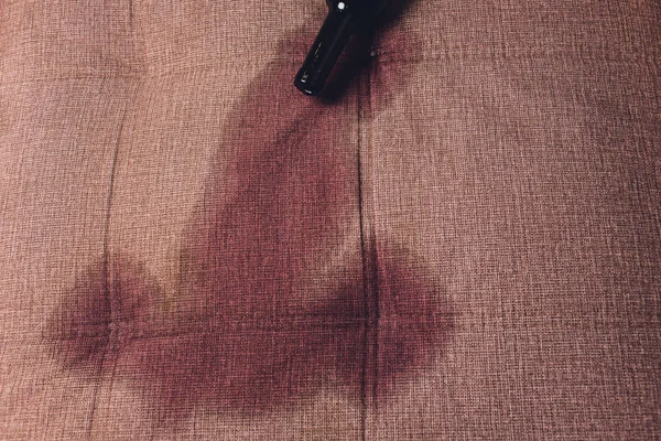 Κόκκινο κρασί χύθηκε σε ένα καναπέ καφέ καναπέ. έπεσε σκούρο μπουκάλι κόκκινο κρασί — Φωτογραφία Αρχείου