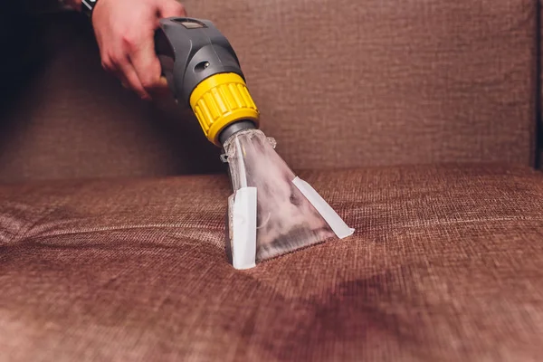 Kanepe kimyasal profesyonel çıkarma yöntemiyle Temizleme. Döşemeli mobilya. Erken bahar temizlik veya normal temizleyin. Kir kaldırmak ışık koruyucu eldiven çalışan Kuru Temizleme