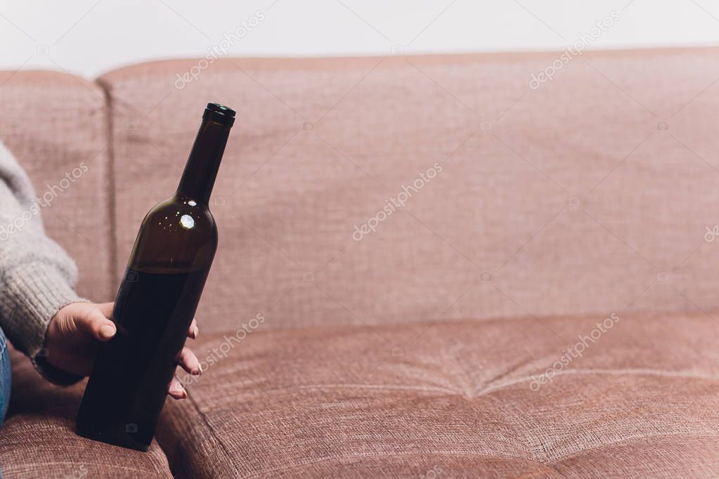 Red wine spilled on a brown couch sofa. dark bottle of red wine dropped