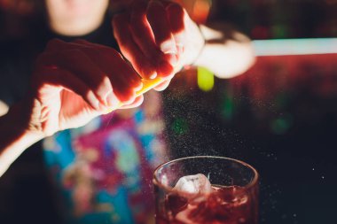 Koyu arka plan üzerinde alkollü içki kokteyl bardağına suyu yağmurlama barmen s elleri dolu.