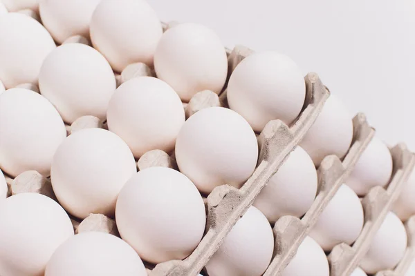 Ovos brancos de uma galinha em embalagem de cartão inofensiva em um contexto branco. 5 embalagens . — Fotografia de Stock