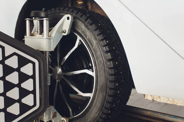 Un coche en el volante del coche Balanceador y Calibrar con reflector láser adjuntar en cada neumático para centrar la conducción ajustar en el garaje . — Foto de Stock