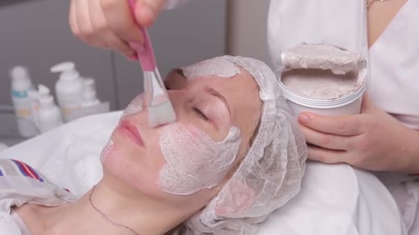 Belle jeune femme ayant un masque cosmétique facial au salon de spa. Fille est avoir un traitement cosmétique . — Video