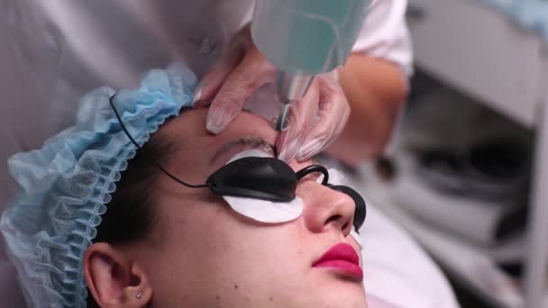 Remoção a laser de uma maquilagem permanente em uma cara. Feche a mulher jovem que recebe a correção de uma tatuagem no procedimento de sobrancelhas. Correção de imperfeições naturais em uma cara . — Vídeo de Stock