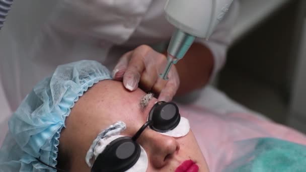 Laser borttagning av en permanent make-up på ett ansikte. Närbild ung kvinna får korrigering av en tatuering på ögonbrynen förfarande. Korrigering av naturliga ojämnheter på ett ansikte. — Stockvideo