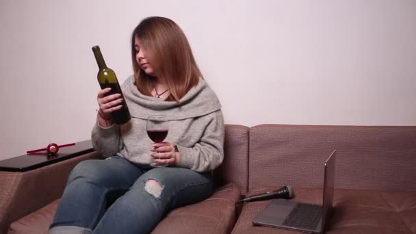 Genç kadın şarap cam, elinde bir şişe şarap etiketinde okuma. — Stok video