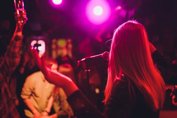 Entertianment at a wedding. A female singer is interacting with the crowd while a man plays an acoustic guitar.