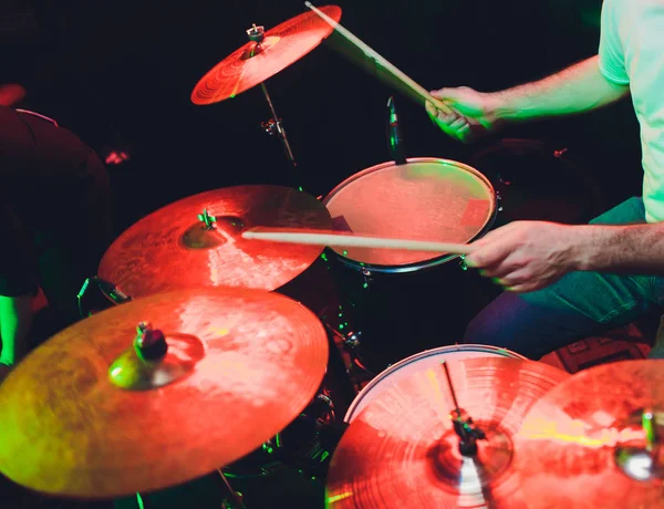 Man plays musical percussion instrument with sticks closeup on a black background, a musical concept with the working drum, beautiful lighting on the stage. — Stock Photo, Image