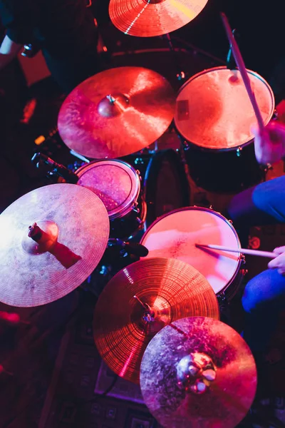 De mens bespeelt muziekpercussie-instrument met stokken close-up op een zwarte achtergrond, een muzikaal concept met de werkende drum, mooie verlichting op het podium. — Stockfoto