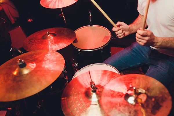 Muziek, mensen, muziekinstrumenten en entertainment concept - mannelijke muzikant of drummer speelt drumstel in studio over vakantie lichten achtergrond. — Stockfoto