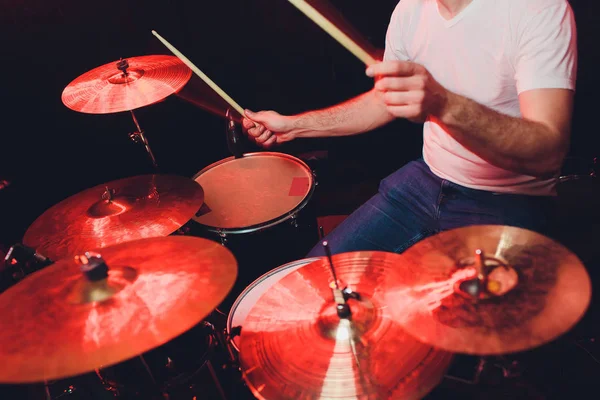 Muziek, mensen, muziekinstrumenten en entertainment concept - mannelijke muzikant of drummer speelt drumstel in studio over vakantie lichten achtergrond. — Stockfoto