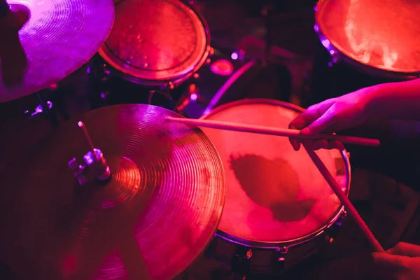 Homem toca instrumento de percussão musical com varas de perto em um fundo preto, um conceito musical com o tambor de trabalho, bela iluminação no palco. — Fotografia de Stock