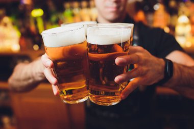 Barman hands pouring a lager beer in a glass. clipart