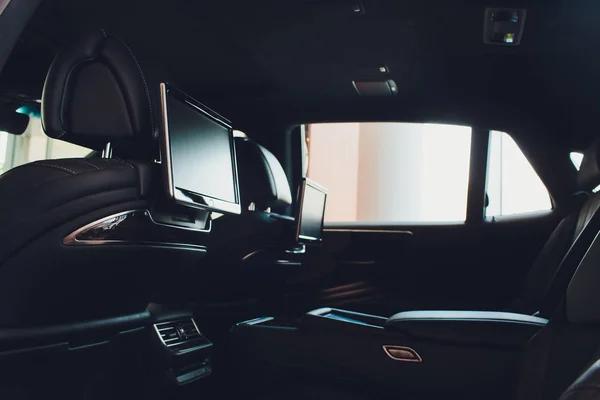 Coche adentro. Interior de prestigio de lujo coche moderno. Tres pantallas de TV para pasajeros con espacio de copia del panel de control de medios y maqueta . — Foto de Stock