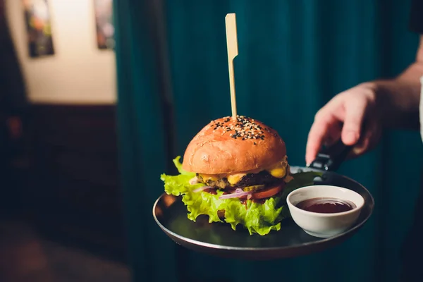 Salada de hambúrguer com batatas fritas em mãos de garçons . — Fotografia de Stock