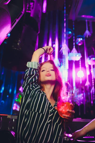 Szczęśliwa Kobieta tańczy w nocnym klubie z drinkami w ręku. — Zdjęcie stockowe