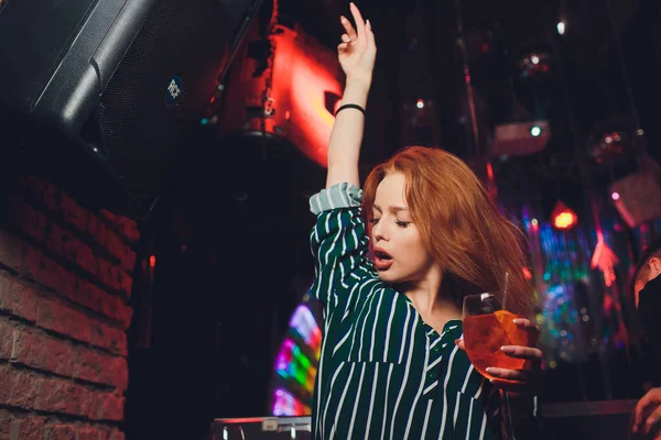 Mujer feliz bailando en el club nocturno con bebidas en la mano . — Foto de Stock