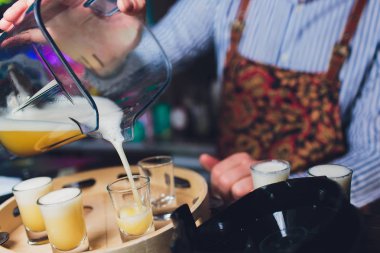 Sarı kokteyller gece kulübünde kokteyl seti. Profesyonel barmen barda küçük gözlük içine alkollü içki içer. Kulüpte kokteyl çekimleri.