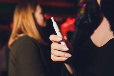 Elektronik Sigara, teknoloji sigara. Tütün sistemi Iqos. Restoran bulanık arka plan üzerinde kadın el.
