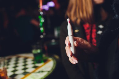 Elektronik Sigara, teknoloji sigara. Tütün sistemi Iqos. Restoran bulanık arka plan üzerinde kadın el.