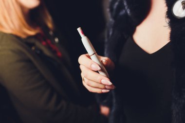 Elektronik Sigara, teknoloji sigara. Tütün sistemi Iqos. Restoran bulanık arka plan üzerinde kadın el.