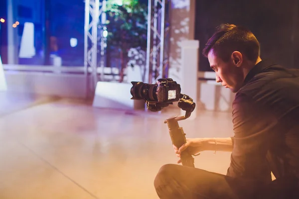 Vídeo profissional segurando câmera no gimbal de 3 eixos. Videógrafo a usar steadicam. Pro equipamento ajuda a fazer vídeo de alta qualidade sem agitar . — Fotografia de Stock