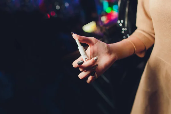 Electronic cigarettes, technology cigarette. Tobacco system IQOS. Female hand on blurred background of the restaurant. black case. — Stock Photo, Image