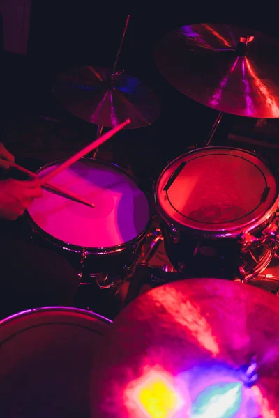 黒の背景にステージ上のドラムセットで演奏する彼の手の中にバチを持つドラマー. — ストック写真