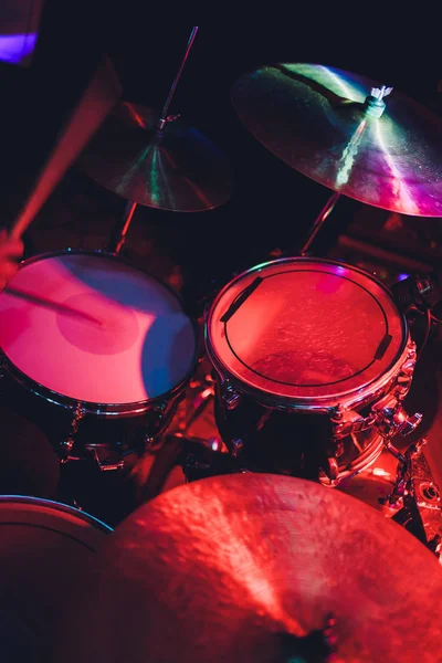 Drummer met een bouten in zijn handen spelen op drum set op het podium op de zwarte achtergrond. — Stockfoto