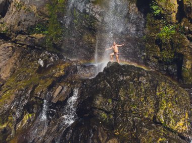 Havada silah ile şelaleler tarafından ayakta çekici adam. Gökkuşağı