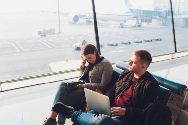 Şık iş çift dizüstü bilgisayar ve havaalanında bekleme salonunda oturan telefon ile çalışıyor. İş seyahati konsepti.
