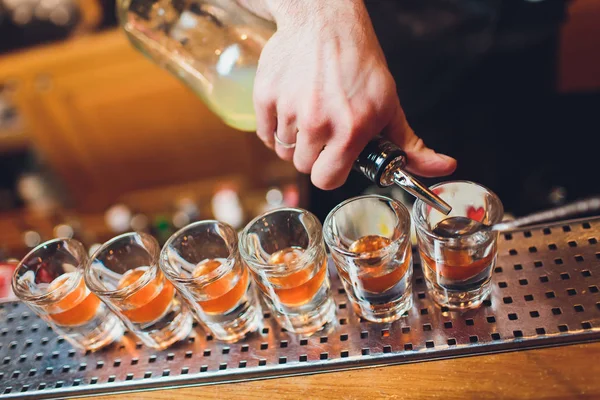 Barkeeper gießt stark alkoholisches Getränk in kleine Gläser an der Bar, Schüsse. — Stockfoto
