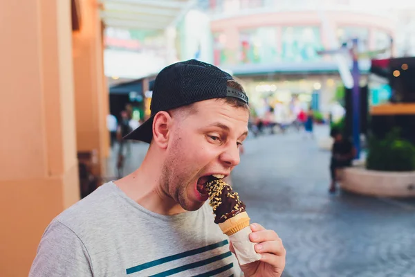 Short bearded man eating ice cream cone in a town street. — Stock Photo, Image