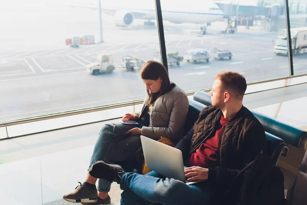 优雅的商务夫妇坐在机场的候机大厅里, 拿着笔记本电脑和手机工作。商务旅行理念. — 图库照片