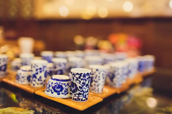 Teapot and cup of tea on woodensurface with blurry nature background.