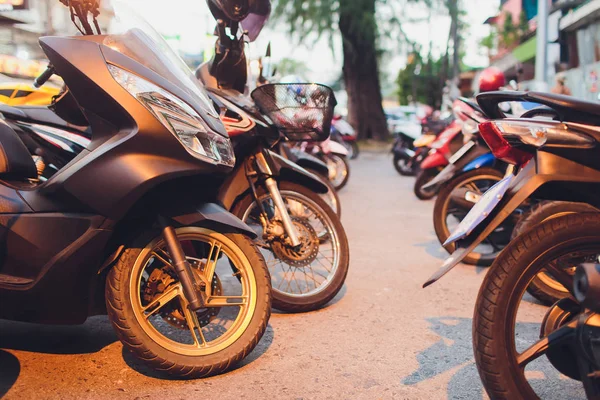 A lot of scooters in the parking, background. Mopeds are on the street. bike for rent.