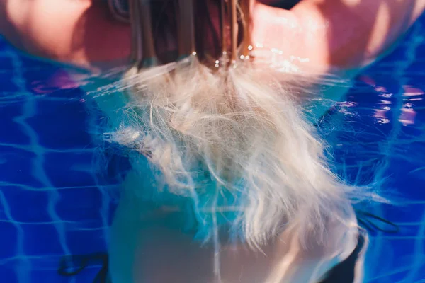 Mooie vrouw verhogen haar hoofd uit het water in een zwembad. — Stockfoto