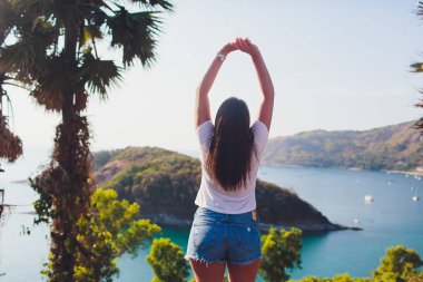 Backview kadın gezgin adalarda bakış açısından rahatlatıcı silah yetiştirme ile poz. mükemmel uyum vücut kadın. Onun tatil zevk Glamour Bayan portresi. Güzel deniz manzarası, seyahat.