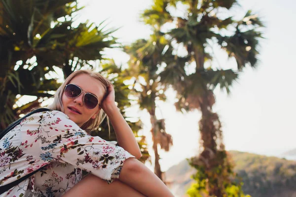 休暇の概念。夏を楽しむ。メガネの若いかわいい女性が海の水の上にヤシの木の上に座っている. — ストック写真