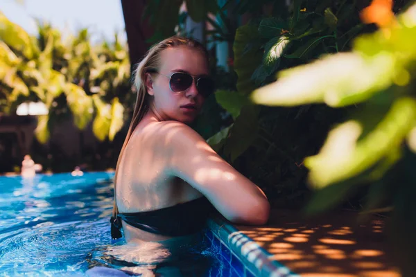 Gyönyörű nő relaxáló a medence víz. Lány az egészséges cserzett bőr, gyönyörű arc, és nedves Hair élvezi nyári nap a forró nyári napon a Pool Edge a Luxury Resort. — Stock Fotó