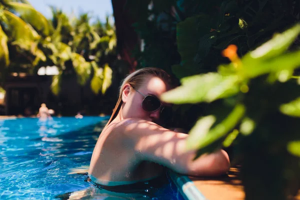 Mooie vrouw ontspannen in zwembad water. Meisje met gezonde gebruinde huid, prachtig gezicht, en natte haren genieten van de zomer zon op hete zomerdag bij zwembad Edge op luxe resort. — Stockfoto