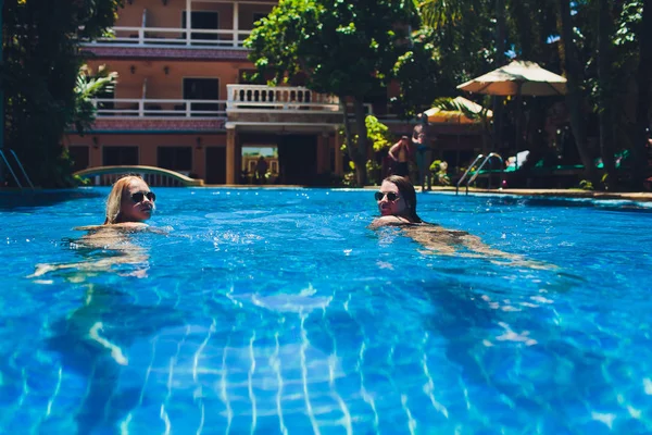 Pár többnemzetiségű lány barátai jól érzik magukat a medence alatt nyaralni. — Stock Fotó