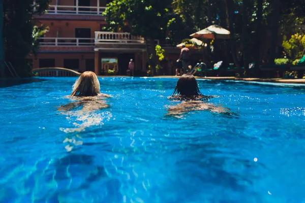 Pár többnemzetiségű lány barátai jól érzik magukat a medence alatt nyaralni. — Stock Fotó
