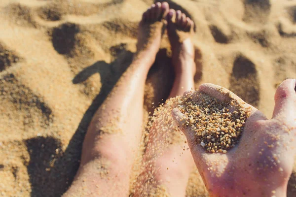 Detalhe de areia correndo através de mãos abertas. No canto da imagem, podemos ver o cabelo da menina que está brincando com a areia . — Fotografia de Stock