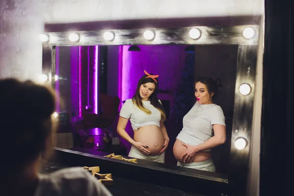 Duas amigas grávidas estão esperando por seus filhos mostrando barriga . — Fotografia de Stock