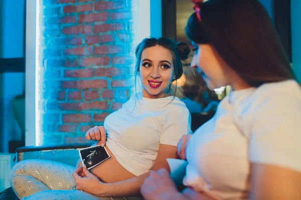 İki çekici hamile kadın ultrason fotoğrafları izlerken. — Stok fotoğraf