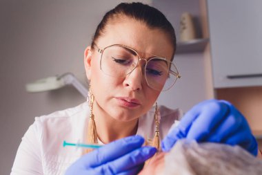 Doktor Kozmetolog, bir güzellik salonunda güzel, Genç bir kadının yüz derisi üzerinde kırışıklıkları sıkma ve yumuşatma için yüz enjeksiyonları prosedürü yapar. Kozmetoloji Cilt Bakımı.