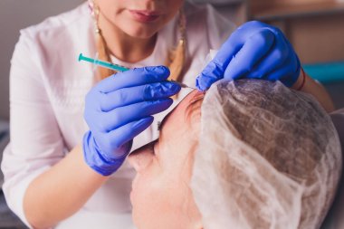 Doktor Kozmetolog, bir güzellik salonunda güzel, Genç bir kadının yüz derisi üzerinde kırışıklıkları sıkma ve yumuşatma için yüz enjeksiyonları prosedürü yapar. Kozmetoloji Cilt Bakımı.