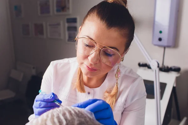 Der Arzt Kosmetologe macht Gesichtsinjektionen zur Straffung und Glättung von Falten auf der Gesichtshaut einer schönen, jungen Frau in einem Schönheitssalon. Kosmetologie Hautpflege. — Stockfoto