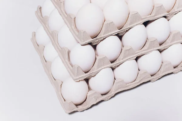 Ovos brancos de uma galinha em embalagem de cartão inofensiva em um contexto branco. 3 embalagens . — Fotografia de Stock